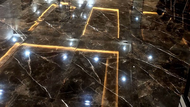 Una habitación amplia con suelo de mármol pulido, un espejo grande y un comedor con sillas y mesas.