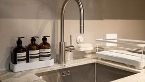 A modern bathroom with a stainless steel sink, a soap dispenser, and a soap dish.