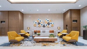 A modern lobby with a central sofa, yellow armchairs, and a coffee table.