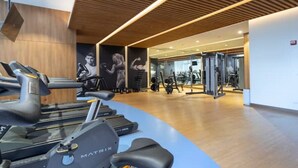 A modern gym with treadmills, weight machines, and a curved blue wall.