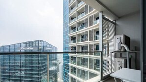A modern hotel room with a large window, a balcony, and a view of other buildings. - Luxury 1BR at BGC Uptown with Free Parking (Taguig City)