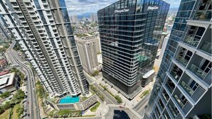 A high-rise building with a modern glass facade, surrounded by other tall buildings. - Luxury 1BR at BGC Uptown with Free Parking (Taguig City)