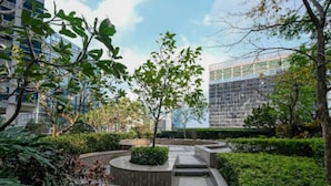 A landscaped courtyard with a central pathway, surrounded by greenery and modern buildings in the background. - New & Modern Uptown BGC 1BR 4pax (Taguig City)