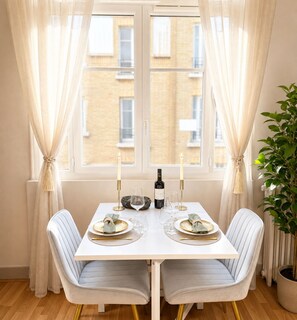 A dining table with two chairs, a bottle of wine, and candles. - 1566 Duranton (Paris)