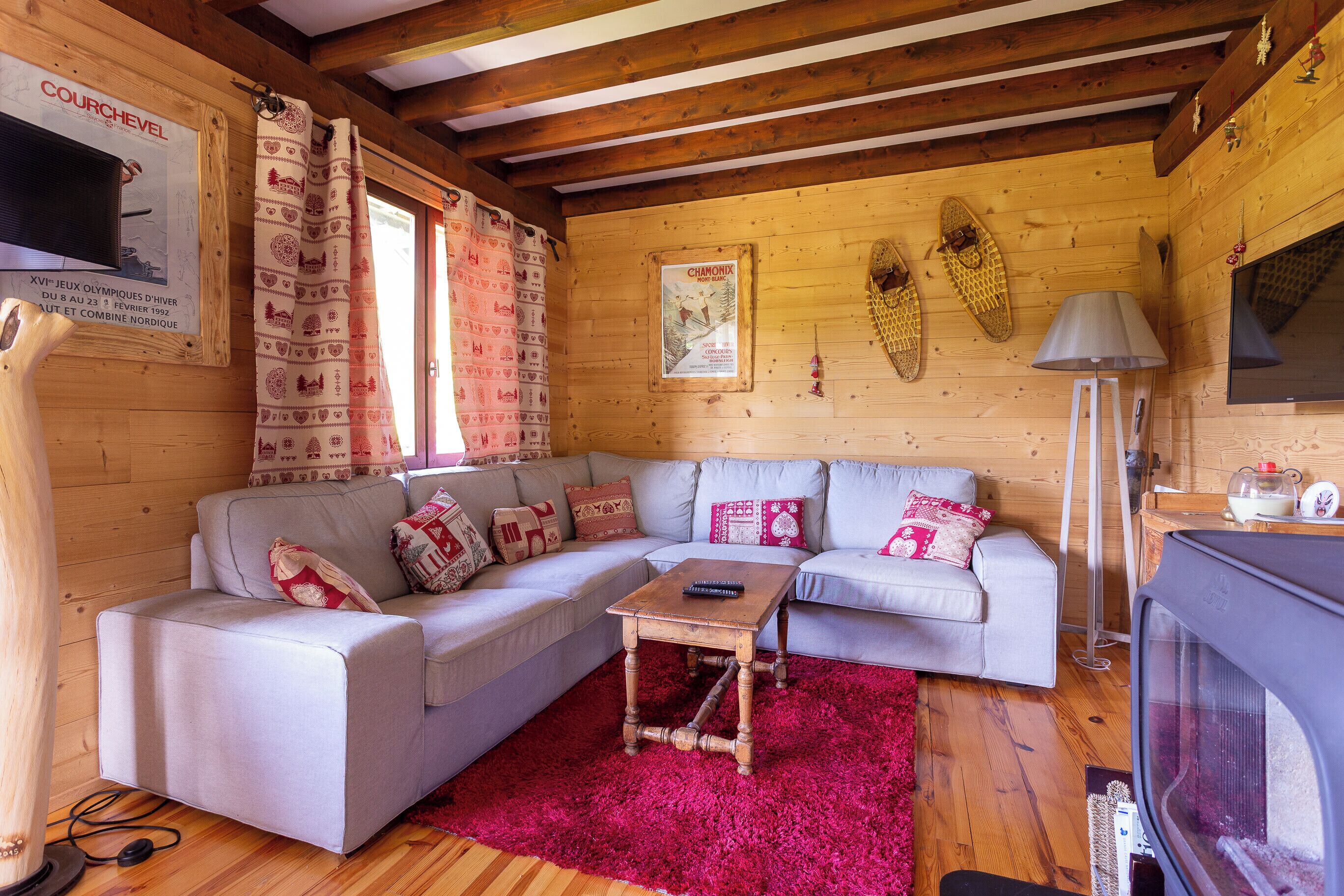 L’intérieur d’un chalet en bois chaleureux et accueillant, avec un canapé d’angle, une petite table en bois et un téléviseur.