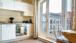 Cocina moderna con armarios blancos, cafetera y vistas a un balcón con una silla.