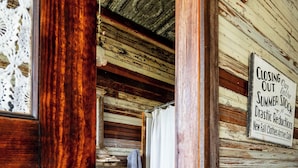 Un interior rústico de madera con un cartel que indica que la tienda está liquidando el inventario de verano.