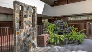Une arche en pierre, un élément décoratif avec de l’eau et une terrasse en bois.