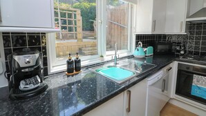 A kitchen with a black countertop, white cabinets, a sink, a toaster, and a coffee maker. - The Hideaway (Dartmouth)