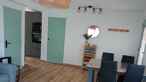 Un salon moderne avec un coin repas, un plancher en bois, un canapé, une table et un téléviseur en arrière-plan.