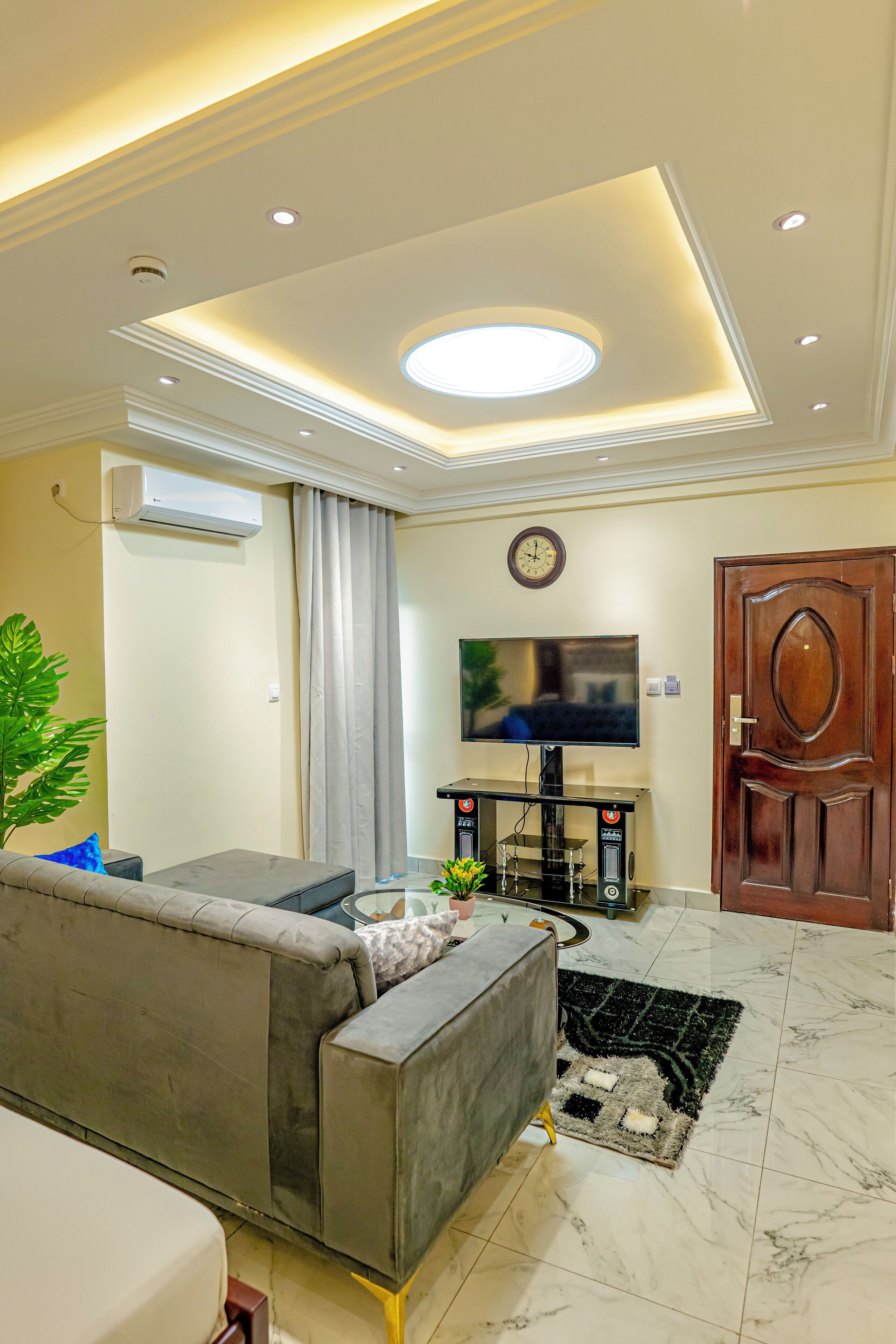 Un salon moderne avec un canapé gris, un téléviseur à écran plat et une porte en bois.