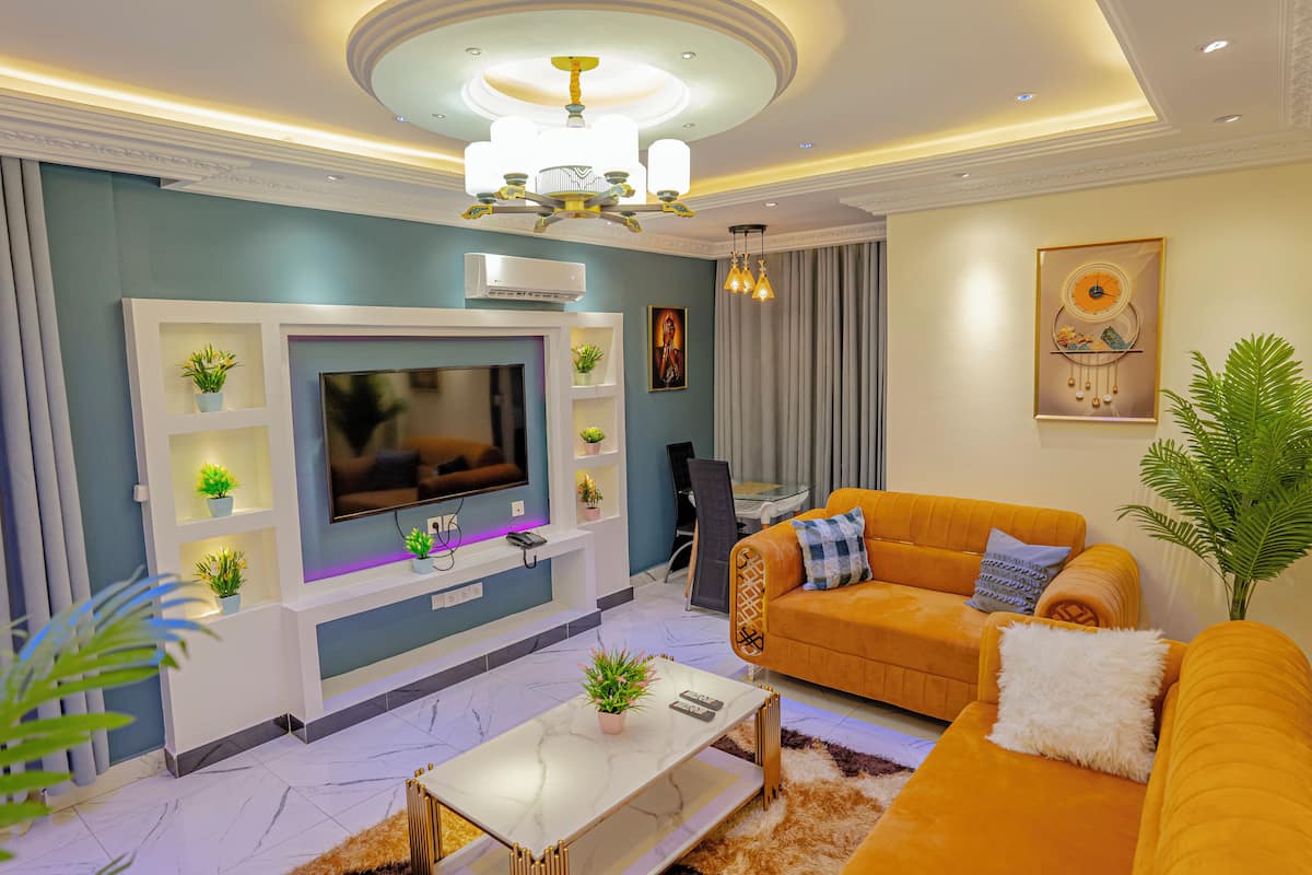 A modern living room with a flat-screen TV, a sofa, a coffee table, and decorative plants.