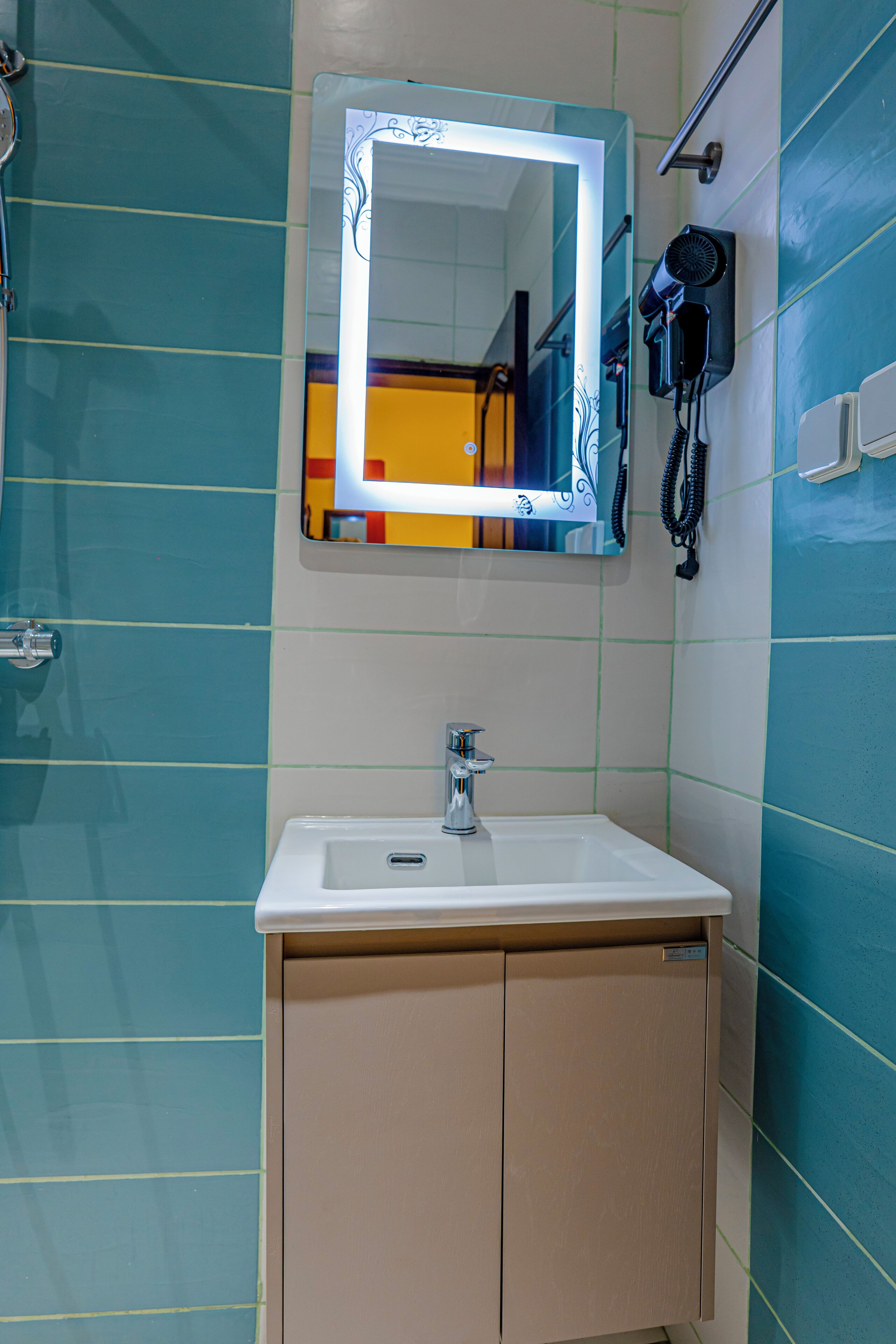 Un baño con lavamanos, espejo y secador de pelo en la pared.