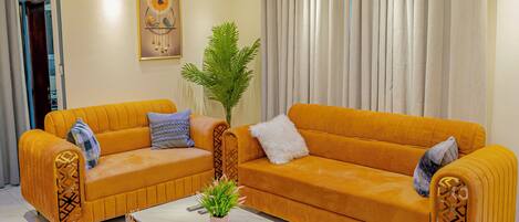 A living room with a yellow sofa, a coffee table, and a ceiling fan.