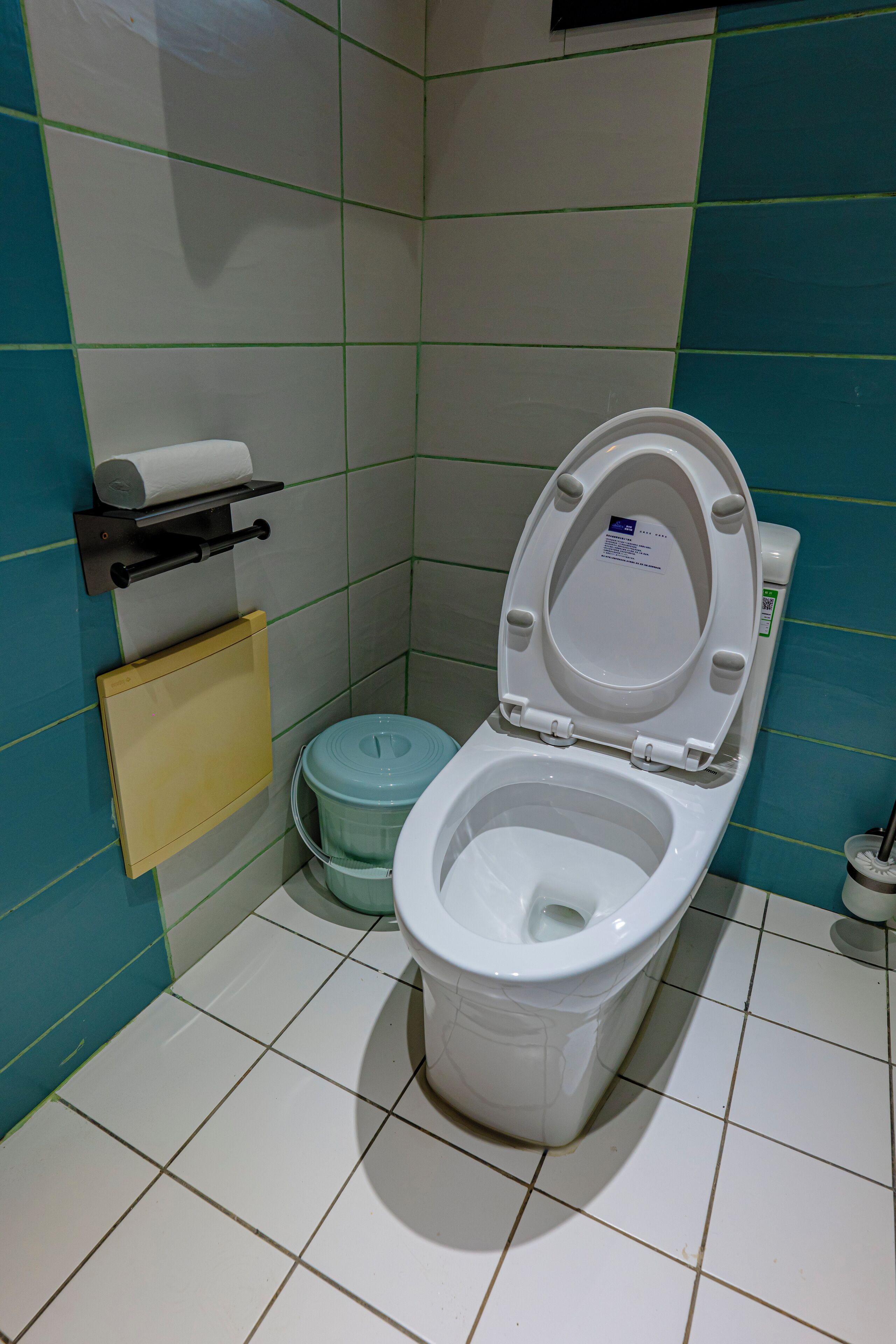 A small bathroom with a toilet, a toilet paper holder, and a trash bin.
