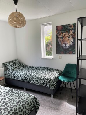 A bedroom with a bed, a chair, a shelf, a window, and a painting. - Detached villa for 5/6 persons, 3 bedrooms, 2 bathrooms, dog welcome, Brouwershaven (Brouwershaven)