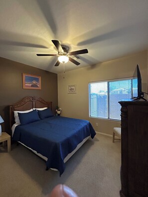 A bedroom with a bed, a ceiling fan, a window with blinds, a nightstand, and a dresser. - Come relax on the covered patio with your favorite beverage and enjoy Santan. (San Tan Valley)