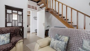 Ein Wohnzimmer mit Treppe, einer Couch und einem Sessel.