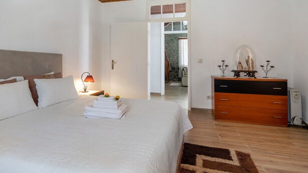 Ein Schlafzimmer mit Bett, Kommode, Lampe und Spiegel.