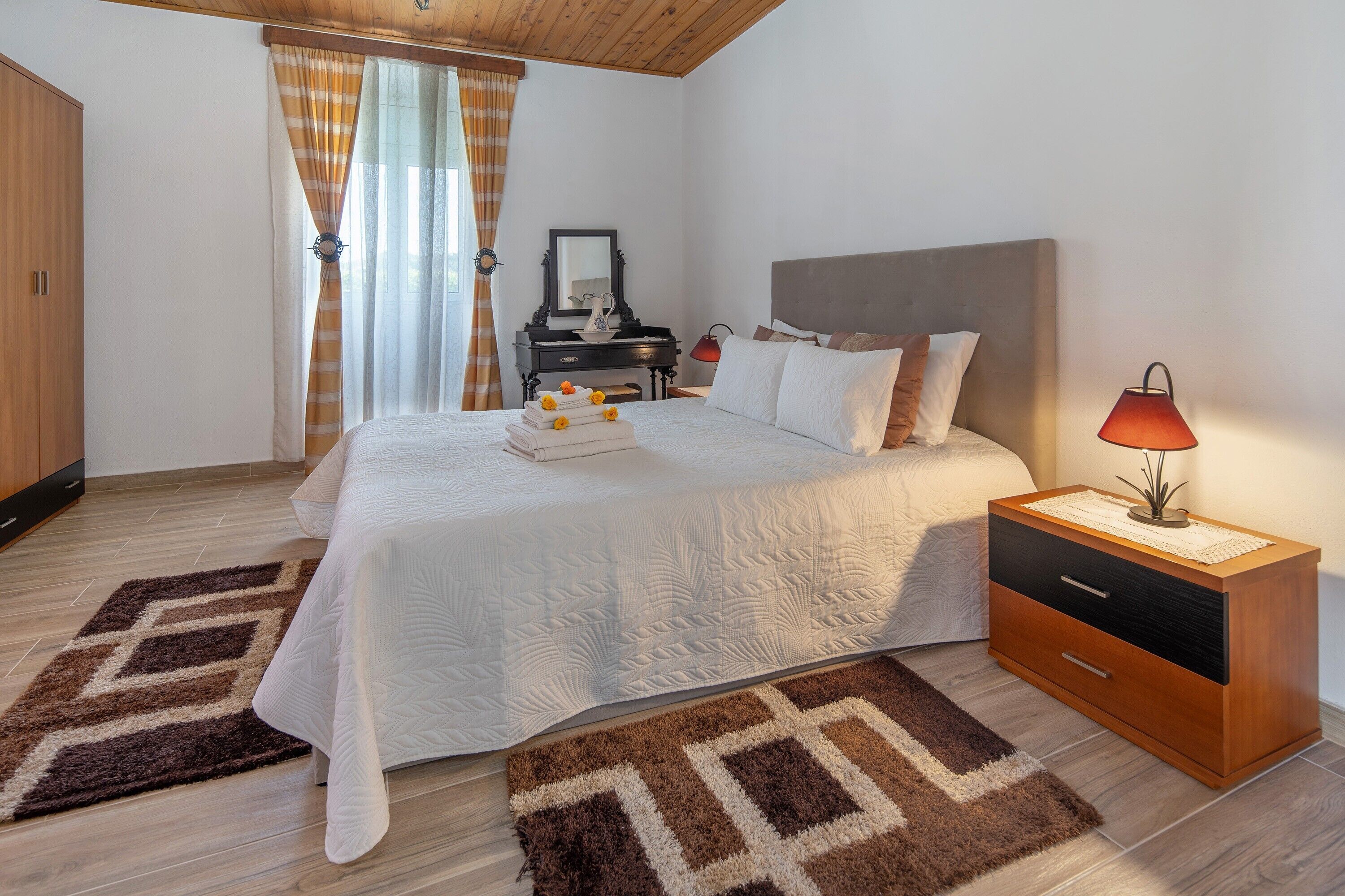 A bedroom with a bed, bedside table, dresser, and a mirror.