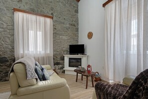 A living room with a stone wall, a fireplace, a television, and a cozy seating area.