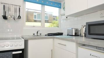 A kitchen with white cabinets, a stove, a microwave, and a toaster.