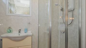 A bathroom with a glass-enclosed shower, a white sink, and a mirror above the sink.