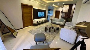 Ein modernes Wohnzimmer mit Flachbildfernseher, Sofas, Couchtisch und einer Treppe.