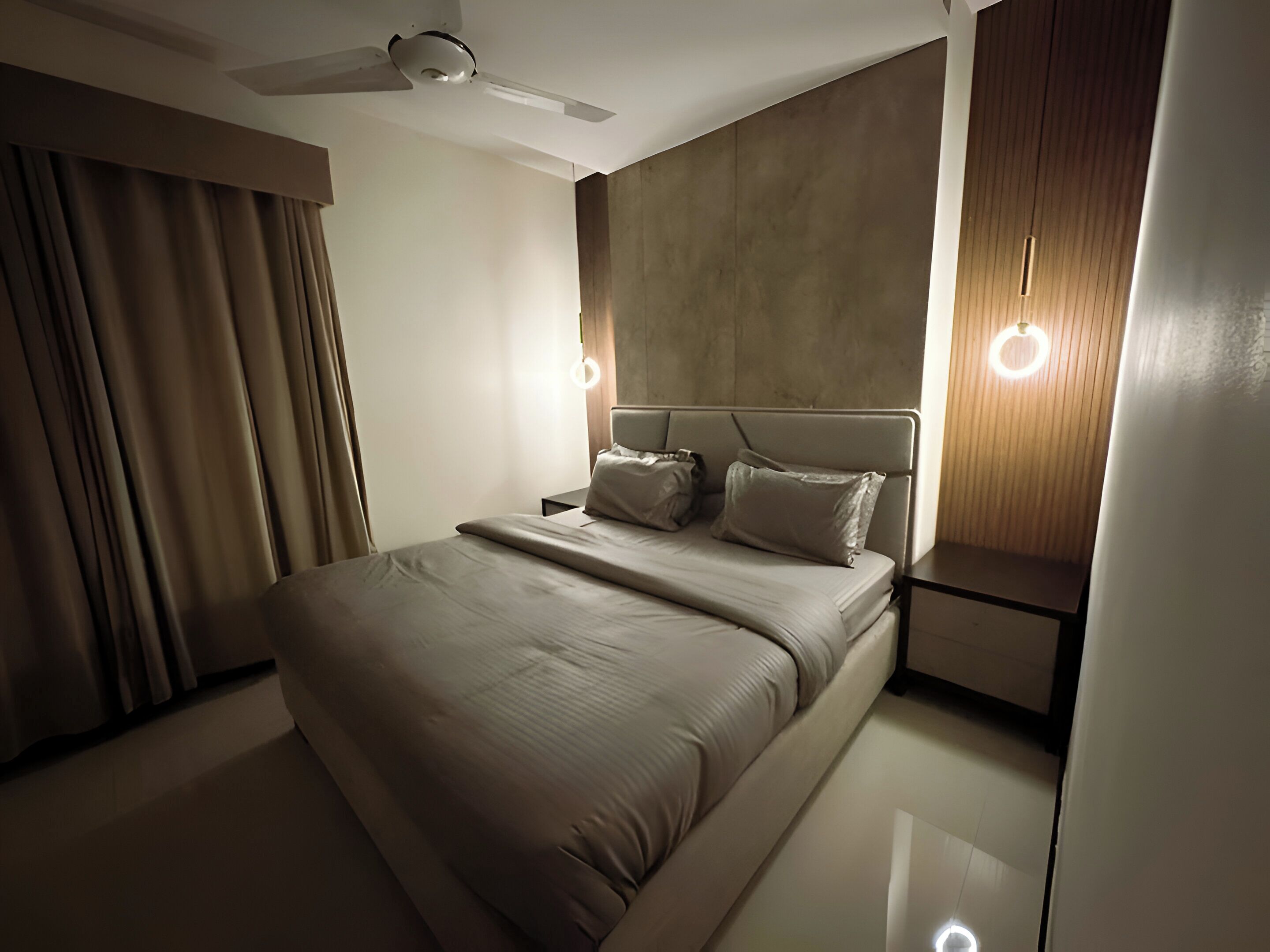 Ein modernes Hotelzimmer mit einem großen Bett, einem Deckenventilator und Nachttischlampen.