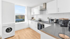 A modern kitchen with white cabinetry, a built-in dishwasher, a large window with a view, and a grey countertop. - Pass the Keys | Bosun's Loft - Superb Views! (Rye)