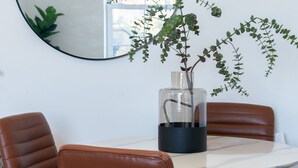 A dining area with a round table, two brown leather chairs, and a vase with a plant. - Pass the Keys | Bosun's Loft - Superb Views! (Rye)