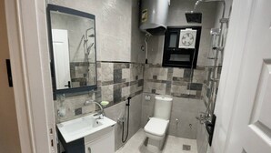 Un bany petit i funcional amb un lavabo, vàter i dutxa.