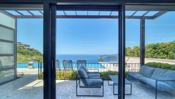 A modern outdoor patio with a pool, seating, and a view of the sea. - Apartment Benita (Sveti Stefan)