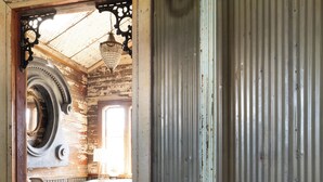 A rustic interior with a wooden floor, a cowhide rug, a vintage chair, and a metal column. - 8 Minutes from Round Top!  Your Silo-Bration Destination
StoneHENge Silo #2 (La Grange)