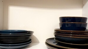 A white shelf with stacked bowls and plates.