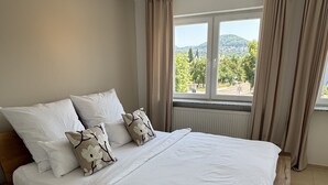 A bedroom with a wooden bed, white bedding, and a window with curtains.
