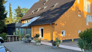 A house with a sloped roof, a gravel driveway, and potted plants.