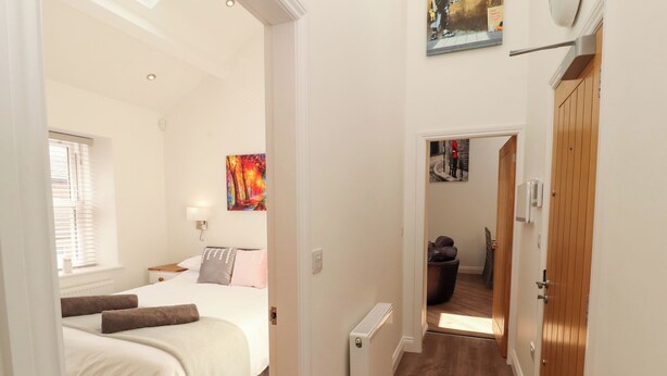 Quarto de hotel com uma cama, radiador, janela com persianas e um quadro na parede.