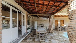 A covered patio with a dining table and chairs, a brick column, and a pool. - Ch Cara Tima Localiza o Piscina e Churrasqueira (Igarata)