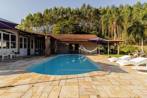 A swimming pool with lounge chairs, a covered patio area, and a view of a forested area. - Ch Cara Tima Localiza o Piscina e Churrasqueira (Igarata)