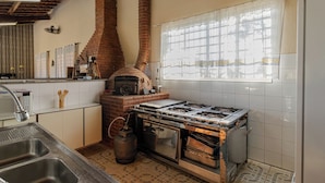 A kitchen with a brick oven, gas stove, and a window with a view. - Ch Cara Tima Localiza o Piscina e Churrasqueira (Igarata)