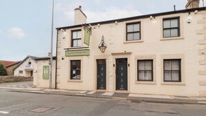 A building with a sign reading "Taps on the Green" and a smaller sign for "Craft Ale, Wine & Gin Bar." - Lakes View Apartment 2 (Carnforth)