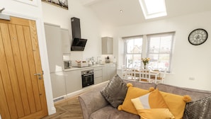 A modern kitchen with white cabinets, a built-in oven, and a black range hood. - Lakes View Apartment 2 (Carnforth)