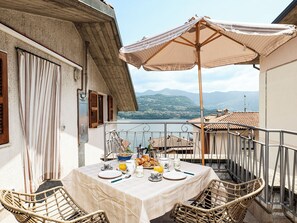 Un balcon avec une table préparée pour le petit-déjeuner, offrant une vue sur un lac et des montagnes.