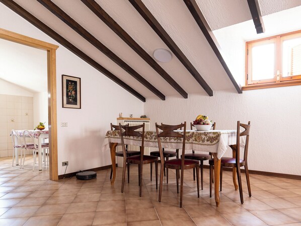 Un coin repas avec une table dressée pour six personnes, entourée de chaises en bois.
