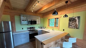 Una cocina moderna con vigas de madera, electrodomésticos de acero inoxidable y una isla grande con taburetes de bar.