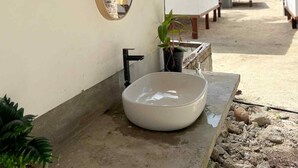 A bathroom with a large mirror, a sink, and a small potted plant.