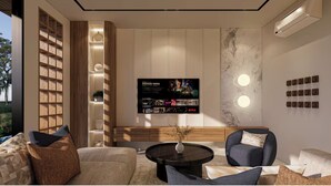 A modern living room with a large flat-screen TV mounted on the wall, a coffee table, and comfortable seating. - Villa Rizière Ubud Center (Bali)