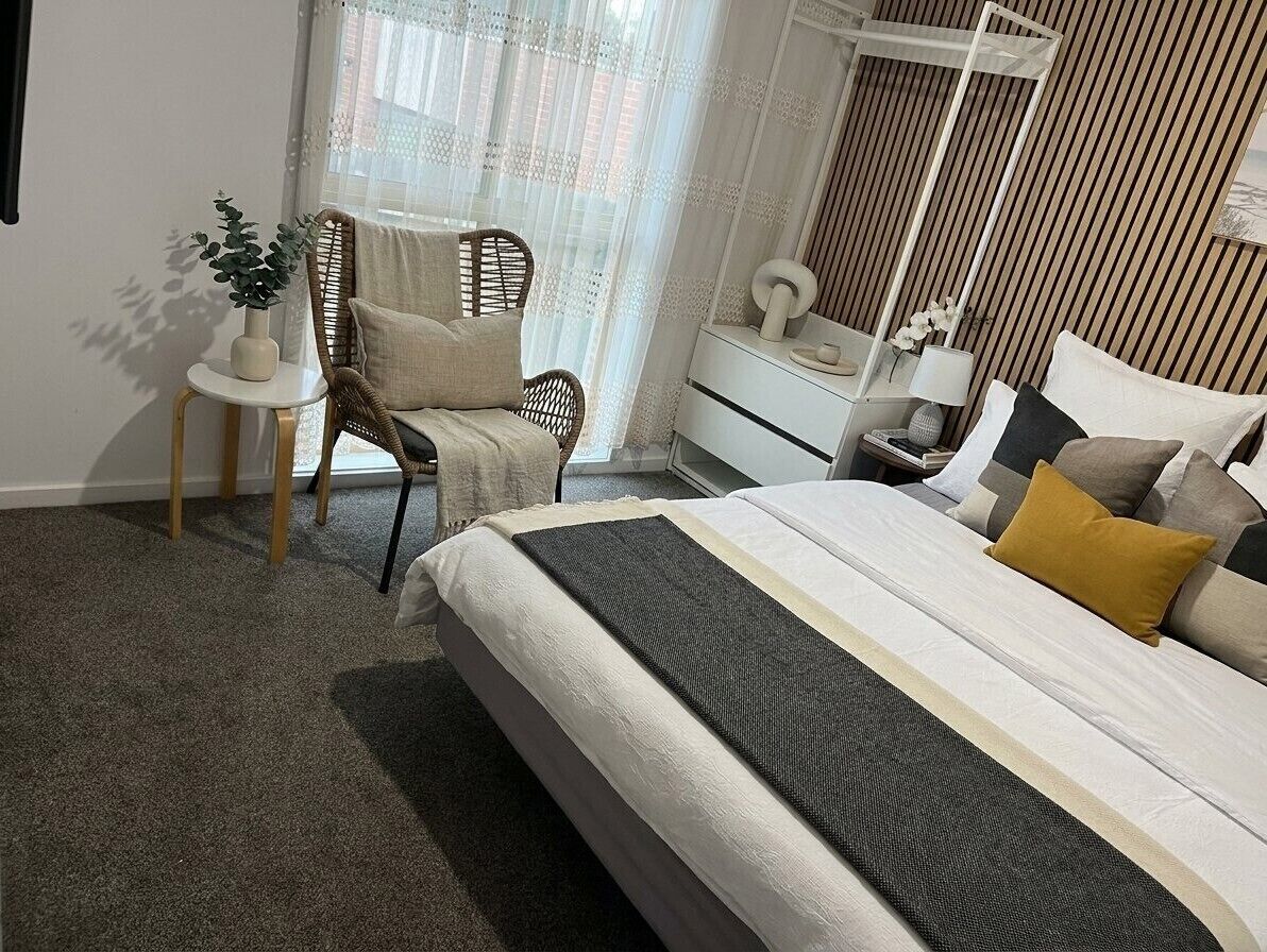A bedroom with a bed, a chair, a bedside table, and a wardrobe.