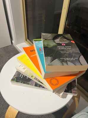 Una pila de libros sobre una mesa blanca cerca de una ventana.
